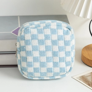 Close-up of blue and white checkered knitted cosmetic bag with zipper on a wooden desk