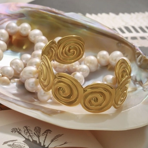 Golden spiral link titanium steel bracelet displayed inside an iridescent seashell