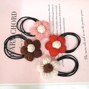 Close-up of four handmade crochet flower hair ties in pink, red, brown, and cream white