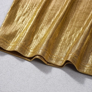 Vue détaillée du tissu plissé métallisé doré et des coutures fines sur la robe