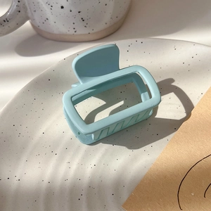 Detailed view of light blue square matte hair claw clip on a ceramic tray for a trendy look