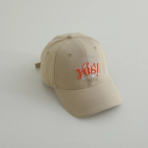 Detail of beige cotton baseball cap with orange 'yes!' 3D embroidery and twill texture