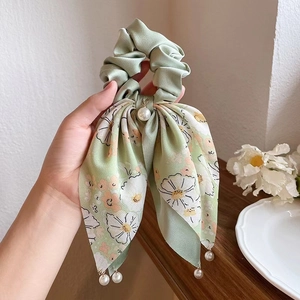 Detail of green floral silk hair scrunchie with bow knot and elegant pearl pendants