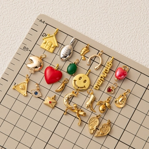 Assortiment de breloques dorées DIY avec cœur, smiley et bottes sur un tapis quadrillé