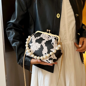Fashionable cow print kiss-lock handbag with pearl chain and gold metal strap