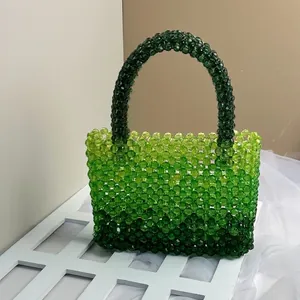 Detail of green gradient acrylic bead handbag on a white display rack with light background