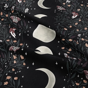 Detail of moon phase tapestry with moth and floral print on soft black fabric