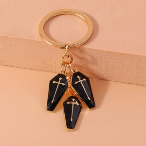 Detail of gothic keychain featuring black coffin charms with golden cross engravings