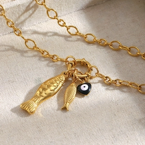Detail of 18K gold-plated necklace with gold fish charms and evil eye heart pendant