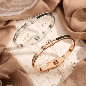 Detailed shot of silver and rose gold zircon bangles on stone surface and linen