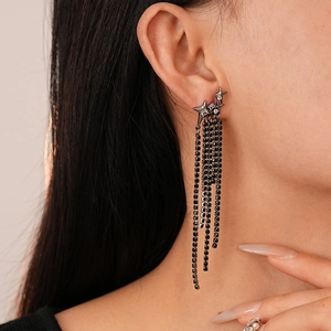 Close-up of black star zircon tassel earrings worn by a model in a luxury dark style