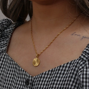 Detail of 18K gold-plated sunburst pendant necklace with a spiral twisted chain