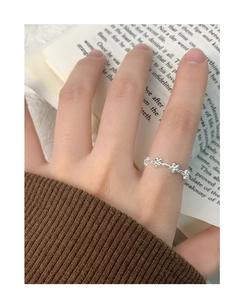 Detail shot of a silver flower ring with petals worn on finger over an open book