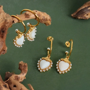 Elegant gold titanium heart earrings with mother of pearl inlay and pearl trim on wood