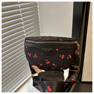 Close-up of black nylon crossbody bag with cherry print and gold zipper detail