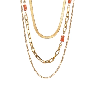 Collana a tre strati in acciaio al titanio dorato con perline arancioni su fondo bianco