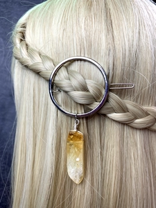 Detail of silver round hair clip with yellow crystal pendant on blonde braided hair
