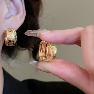 Macro detail of 18K gold plated hoop earrings with elegant textured ripple finish