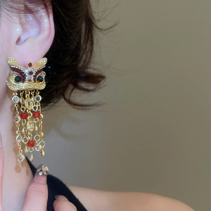 Détail de boucles d'oreilles danse du lion avec glands de perles rouges et strass