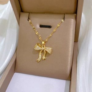 Elegant gold bow necklace with white zircon pavé on a silk background in jewelry box
