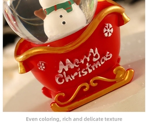 Detailed view of Christmas snow globe featuring a snowman and red sleigh base with Merry Christmas