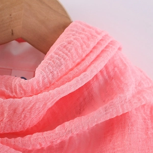 Detailed macro view of pink crinkled cotton linen fabric texture on a wooden hanger