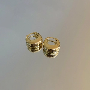 Détail de boucles d'oreilles huggie dorées en U avec un design élégant en goutte d'eau