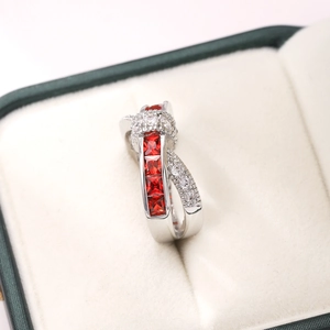 Macro detail of silver crossover ring with square red zircon and pavé crystals in a box