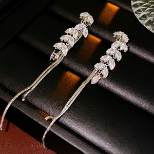 Macro shot of silver wheat chain tassel earrings with marquise-cut crystals on black leather