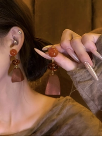 Detail of vintage wooden triple-layered drop earrings featuring a warm amber color palette