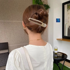 Macro view of a matte beige translucent hair claw clip on a stylish bun hairstyle