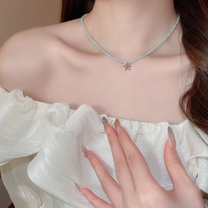 Close-up of light blue glass bead necklace with a silver starfish pendant on a woman's neck