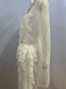 Dettaglio del ricamo floreale in pizzo bianco e delle balze a strati sul vestito elegante