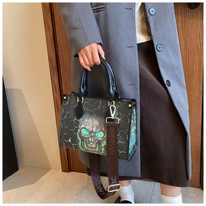 Detail of skull print tote bag featuring green glowing eyes and wide jacquard strap
