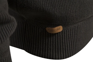 Macro detail of dark green knit texture and brown leather logo patch on a sweater
