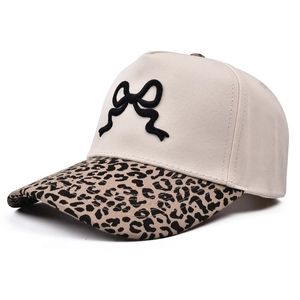 Dettaglio del ricamo fiocco 3D nero e tesa leopardata su un cappellino da baseball