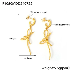 Detailed view of 18K gold plated titanium bow earrings with rhinestones and tassels