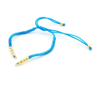 Close-up of blue braided cord bracelet with adjustable closure and gold metal beads