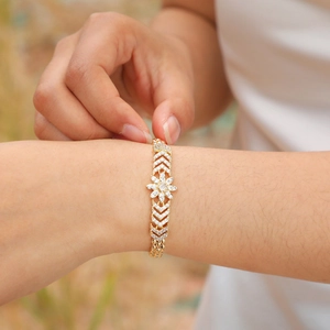 Detailed close-up of a gold-plated flower bracelet featuring V-shaped links and zircons
