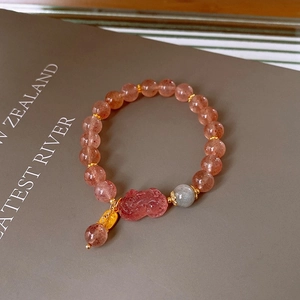 Close-up of strawberry quartz beaded bracelet with pink Pi Xiu charm and golden accents