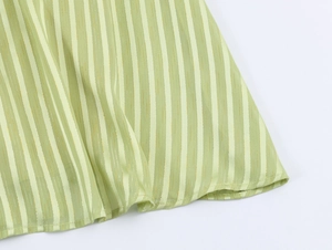 Macro shot of the vertical striped hem and fine stitching on a light green dress