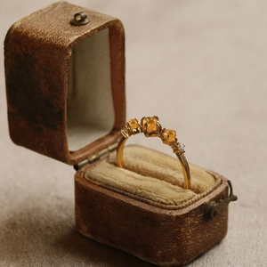 Detailed shot of golden ring with amber gemstones in a vintage brown jewelry box