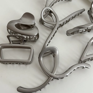 Matte silver metal hair claw clips set with heart and geometric designs on white background