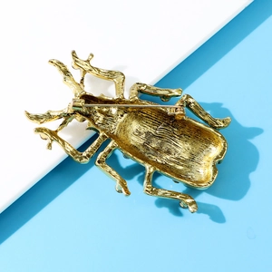 Detailed back view of beetle brooch featuring golden alloy texture and secure pin clasp