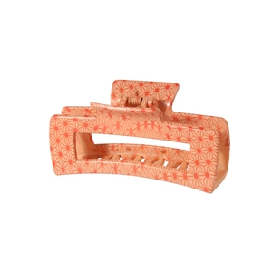 Detail view of large rectangular hair claw clip with orange geometric hemp leaf pattern