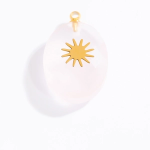 Macro detail of oval pink gemstone pendant with gold sunburst inlay and top ring