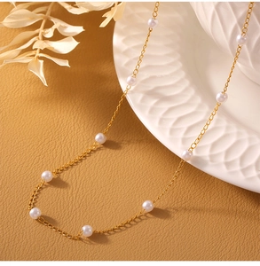 Detail of elegant gold-plated titanium necklace featuring delicate white pearls on a tray