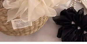 Detailansicht großer Haarklammern aus Chiffon-Blüten in Cremeweiß und Schwarz mit Organza