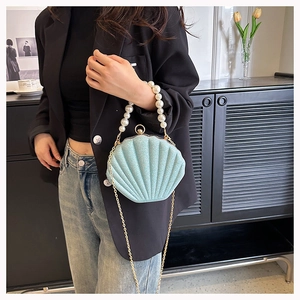 Detail of light blue shell bag featuring a pearl handle and sparkling finish texture
