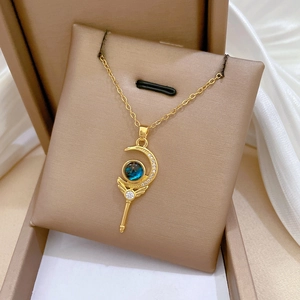 Detail view of a gold magic wand moon necklace with blue gemstones in a jewelry box